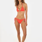 Woman wearing a red bikini on a white background, looking at the camera