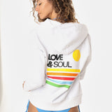 Woman wearing a white hoodie with 'Love & Soul' text and colorful stripes, standing against a white background.