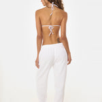 Back shot of woman wearing a white bikini and sweatpants on a white background