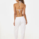 Back shot of woman wearing a white bikini and sweatpants on a white background