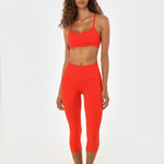 Woman in poppy athletic set looking at the camera.