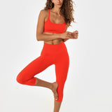 Woman in poppy athletic set in yoga pose.