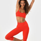 Woman in poppy athletic set posing.