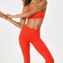Woman posing wearing poppy colored sports bra and leggings.