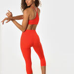 Woman in poppy athletic set looking over her shoulder.