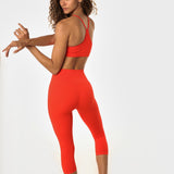 Woman in poppy athletic set looking over her shoulder.